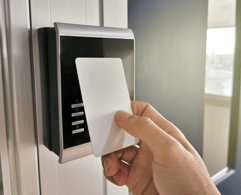 A person using an RFID card to access a secure door at their office.