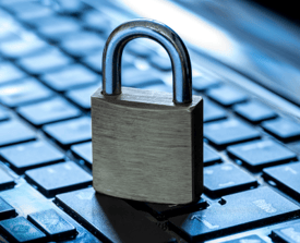 A padlock sitting on top of a darkened laptop keyboard with a blue tint to the background.