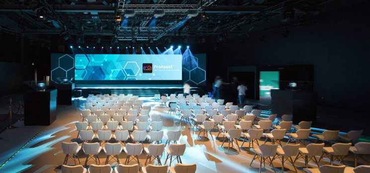 A large venue with a wide video wall in front and chairs facing it.