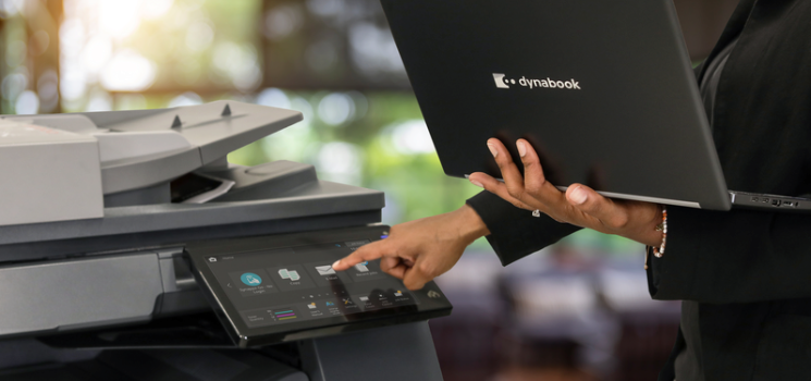 A person using a Dynabook laptop at a multifunctional printer.