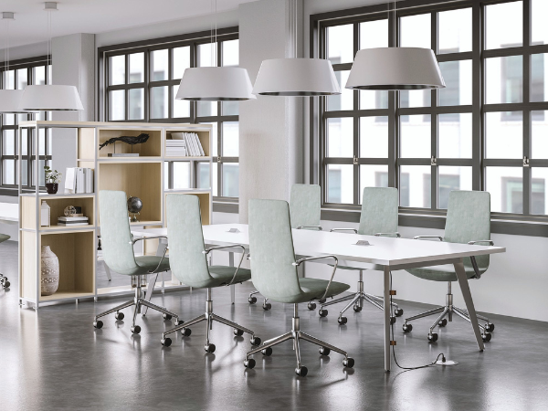 A completed meeting table with chairs surrounding it, lights, and a bookshelf.