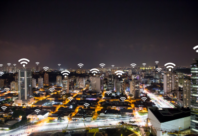 A city at night with icons of wifi connections placed on top of several buildings indicating public wifi is available.