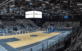 A large basketball stadium with a 4 sided video wall hanging over center court.