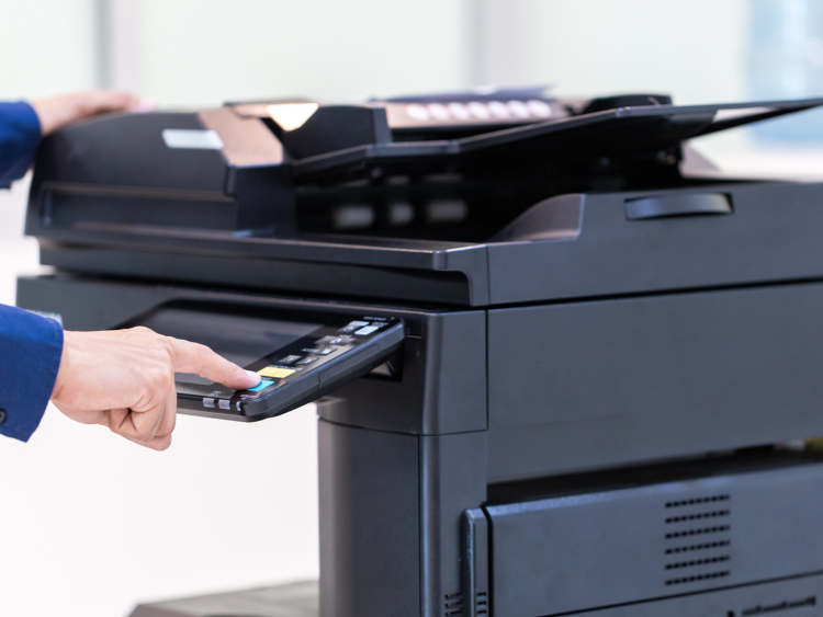 A person pressing a button on a multifunctional printer (MFP)