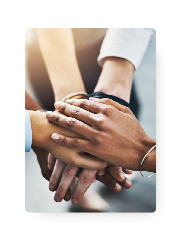 A picture of people's hands stacked on top of one another in a huddle.