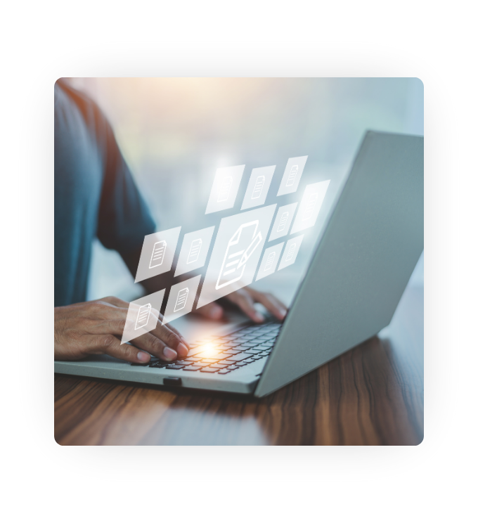 A person at a desk typing on a laptop with digital file icons floating over the keyboard.