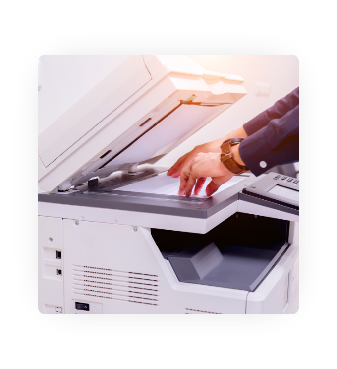 A person using a scanner on a multifunctional printer to copy a piece of paper.